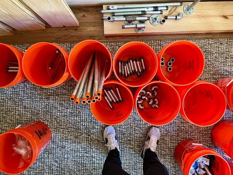 Galvanized steel plumbing pipes and fittings sorted into orange buckets, brought to you by Home Depot®.