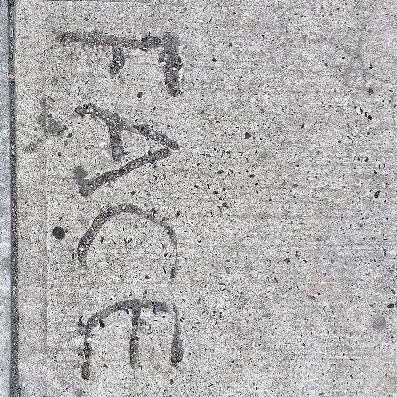 The word 'FACE' permanently etched into a concrete sidewalk.