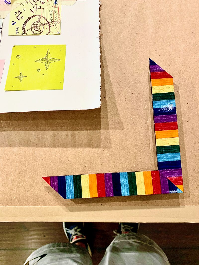 A multichromatic striped frame sample sitting on construction paper.